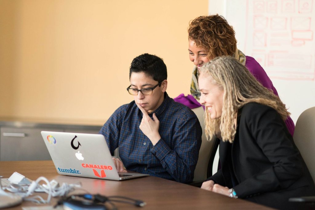 Group of 3 professionals meeting together and working on laptop